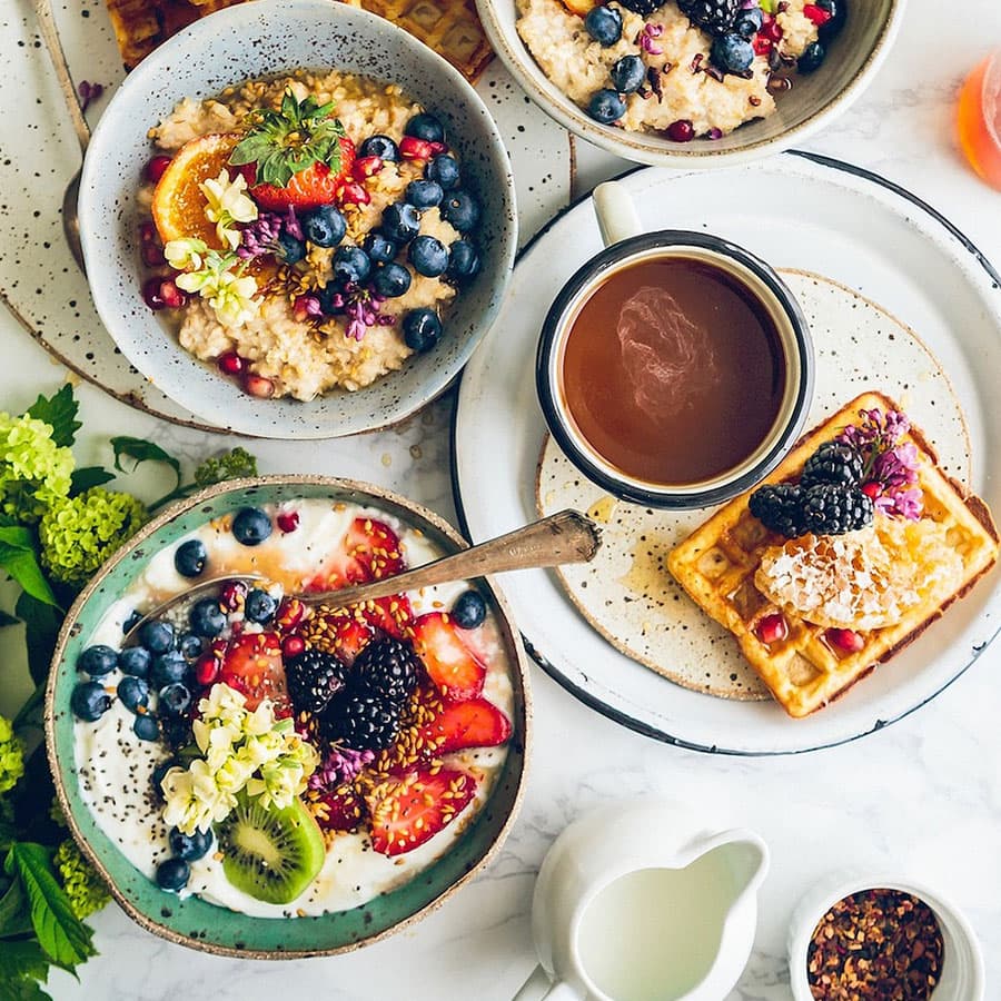 Breakfast table with waffles, coffee, oatmeal with berries