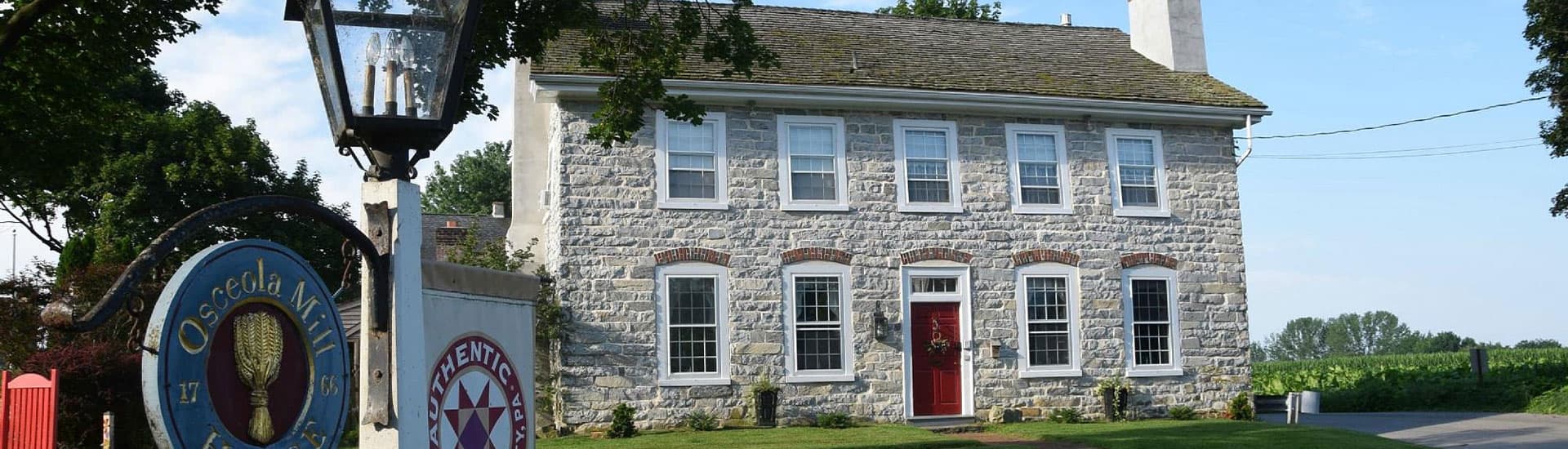 Historic stone building with red door and vintage signage.