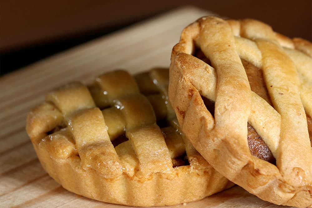 Two small lattice-top pies on a wooden surface.