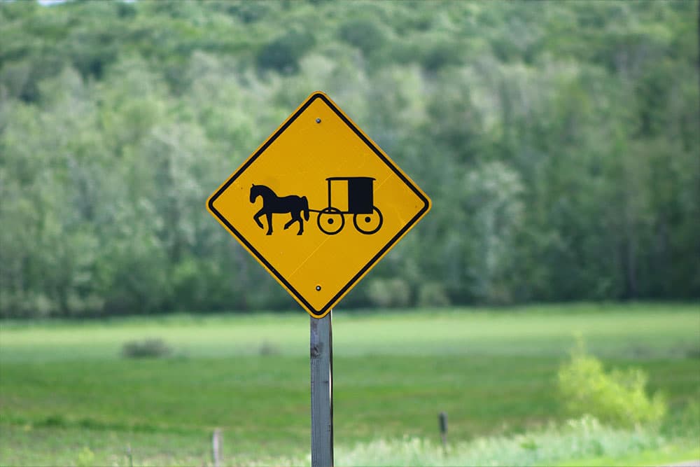 A yellow warning sign depicting a horse and buggy.
