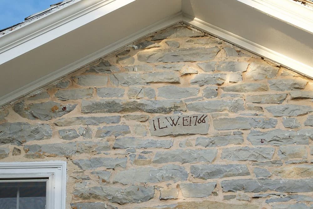 A stone wall with an inscription of "JLW E 1766" near the roofline.