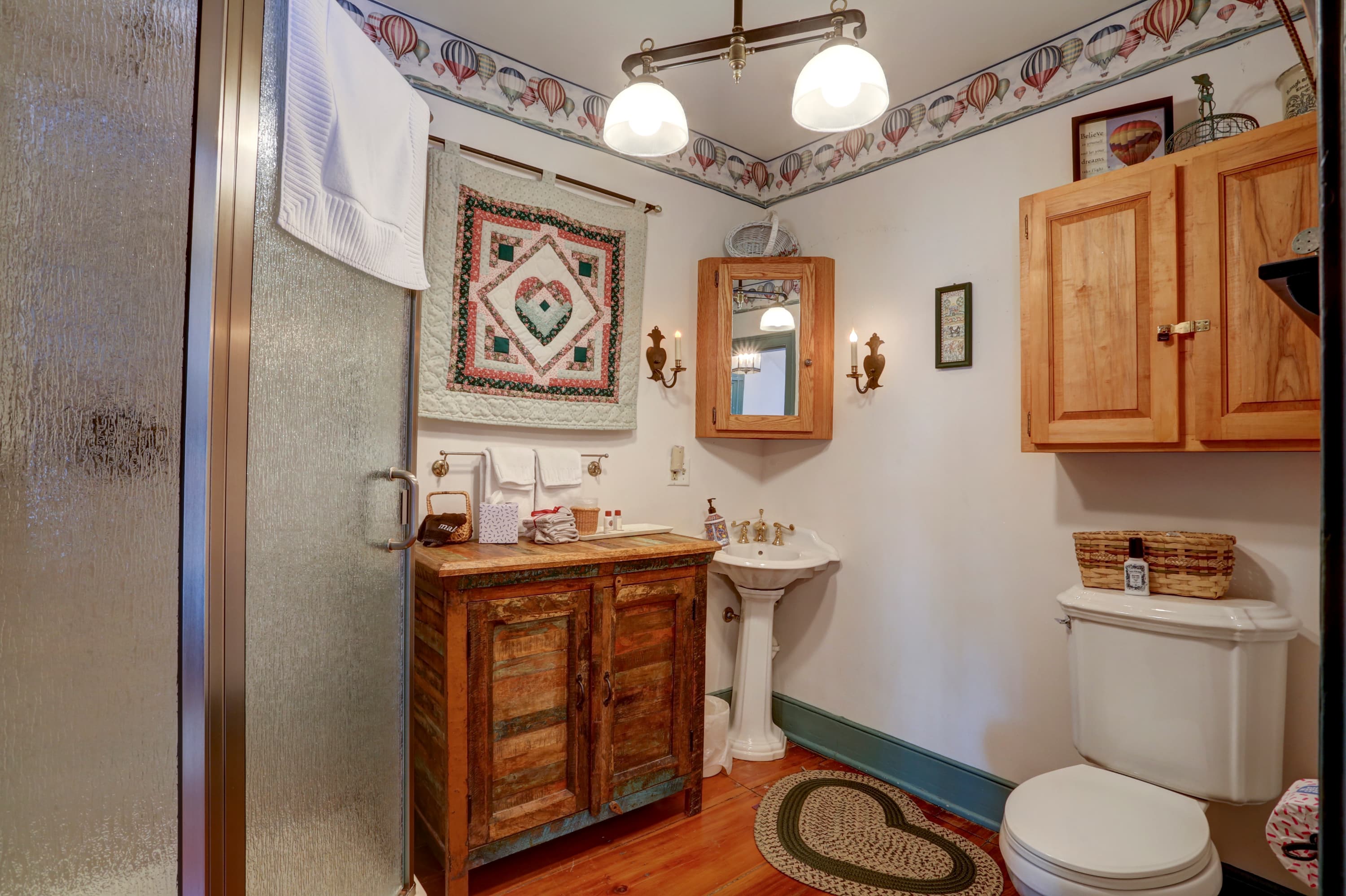 Bathroom with shower with a glass door, a wooden vanity with a sink, and a toilet.